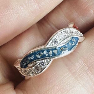 May include: A white ceramic mug with a colorful floral design. The mug features a variety of flowers in shades of pink, purple, and yellow, with green leaves. The handle is also white.