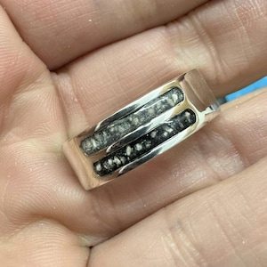 May include: A silver ring with a black and white inlay. The inlay is made of a material that looks like wood or bone.