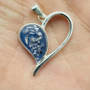 Peut inclure: Pendentif en argent en forme de cœur avec un insert en résine bleue contenant des paillettes blanches et noires.