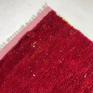 a close-up view of a red, textured carpet or rug with a pink border.