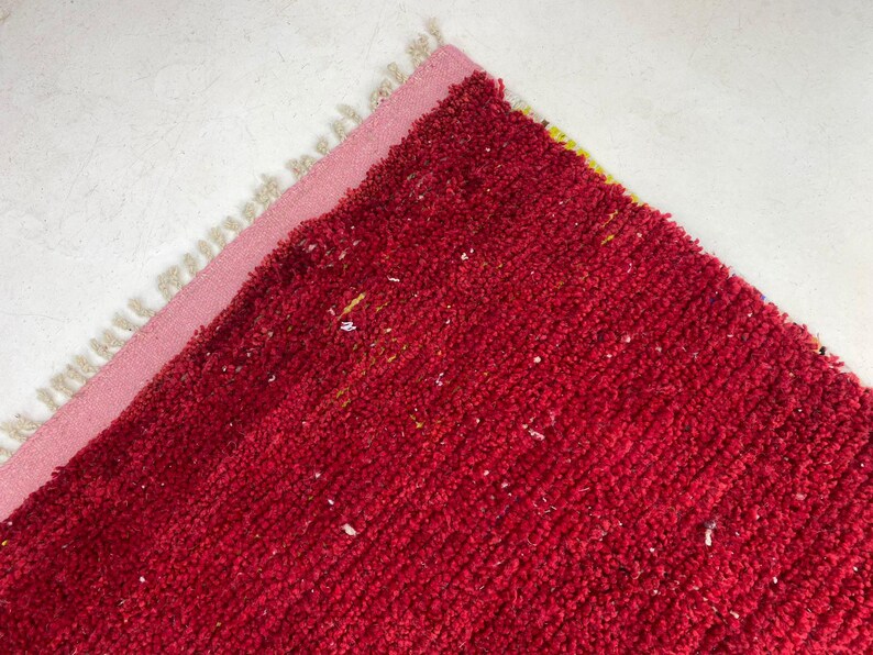 a close-up view of a red, textured carpet or rug with a pink border.