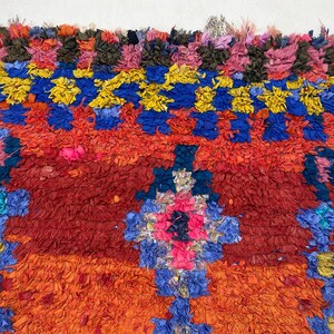 The image is a vibrant, colorful textile with a variety of hues, including red, blue, yellow, and orange. The textile appears to be a rug or a large woven piece, with intricate patterns and designs. The image is not a single, continuous scene but rather a collection of individual images that come together to create a larger, visually striking composition.