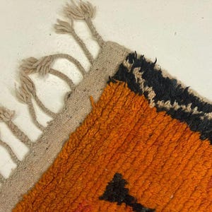 a close-up view of a vibrant, multicolored rug with a striking orange and black pattern.