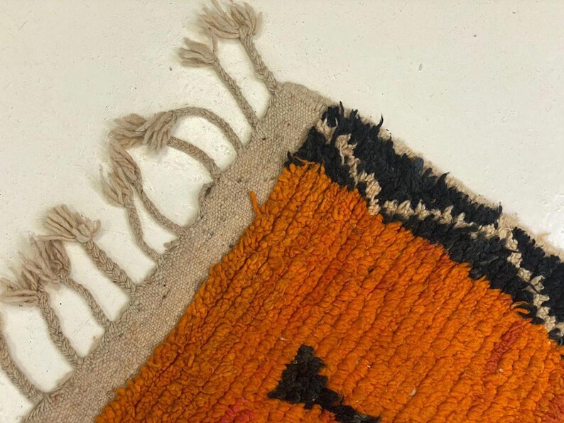 a close-up view of a vibrant, multicolored rug with a striking orange and black pattern.