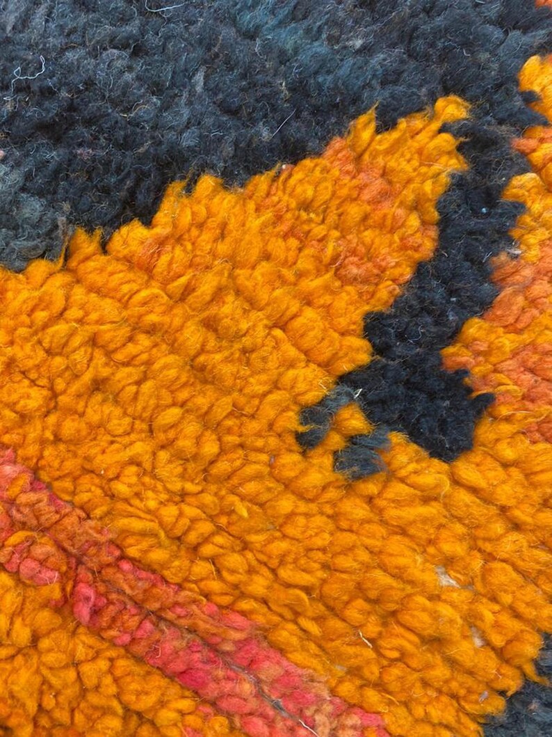 The image is a close-up of a vibrant, textured fabric with a striking pattern of orange and black hues.