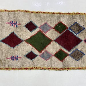 a colorful, geometric rug with a diamond pattern in various shades of green, red, and yellow.