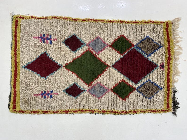 a colorful, geometric rug with a diamond pattern in various shades of green, red, and yellow.