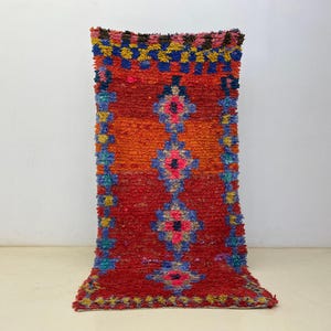 A vibrant, colorful rug with a geometric pattern of red, orange, yellow, and blue hues.