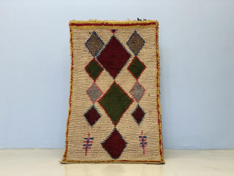 A colorful, geometric rug with a diamond pattern and various shades of green, red, and beige.