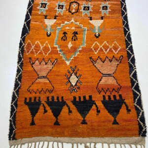 a vibrant, intricately designed rug with a striking orange and black color scheme. The rug is adorned with various geometric patterns and shapes, creating a visually captivating piece of art.