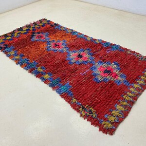A vibrant, multicolored rug with a geometric pattern lies on a white floor.