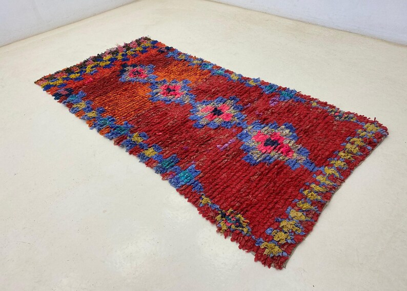 A vibrant, multicolored rug with a geometric pattern lies on a white floor.