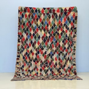 Peut inclure: Un tapis fait à la main aux motifs de losanges colorés. Le tapis présente une variété de couleurs, notamment le rouge, le vert, le bleu et le marron. Le tapis est fait d'un matériau épais et tissé, probablement utilisé comme revêtement de sol.