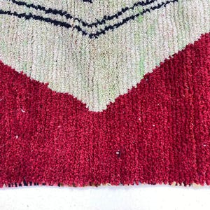 a close-up view of a red and white patterned rug or carpet, with a geometric design in shades of green and white.