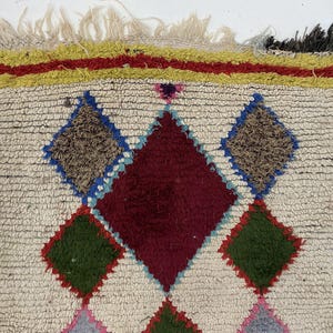 a vibrant, colorful rug with a geometric pattern of diamonds and squares in various shades of red, green, and blue.