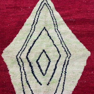 a close-up view of a red and white rug with a geometric pattern in black and white.