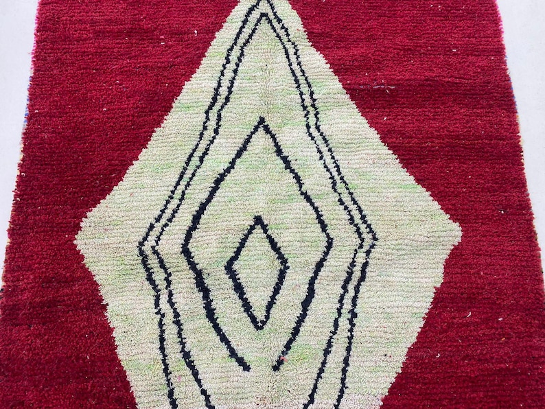 a close-up view of a red and white rug with a geometric pattern in black and white.