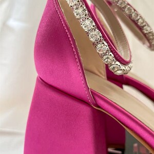 May include: Pink satin heeled sandals with a crystal embellished ankle strap.