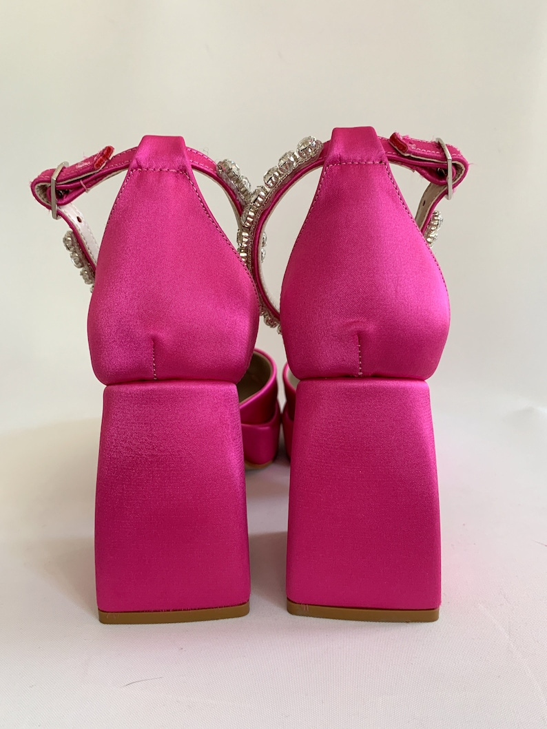 May include: A pair of pink satin heeled sandals with a chunky block heel and a crystal embellishment on the ankle strap.