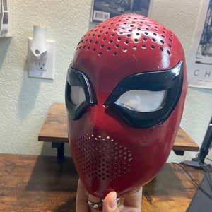 May include: Red and black Spider-Man mask with a mesh eye covering and a perforated design.