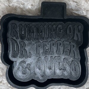 May include: Black 3D printed cookie cutter with the text "Running on Dr. Pepper & Queso".