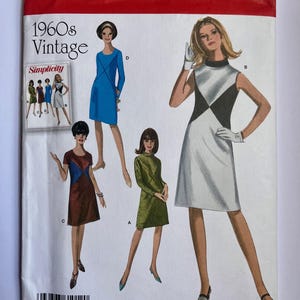 May include: Vintage Simplicity sewing pattern from the 1960s. The pattern features illustrations of women's dresses in various styles, including a blue dress with a diamond design and a white dress with a black diamond design. The pattern size is U.S. 20W-28W.