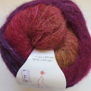 Pu&ograve; includere: Un gomitolo di filato multicolore nei toni del viola, rosso e oro. L'etichetta indica che il filato pesa 100 grammi e misura circa 400 metri. Il filato &egrave; un mix di materiali, tra cui il 20% di nylon.