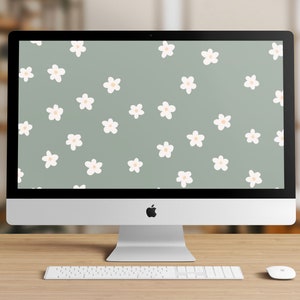 Peut inclure: Un ordinateur iMac argenté avec un clavier et une souris blancs sur un bureau en bois. L'écran affiche un motif de fleurs blanches à centres pêche sur un fond vert clair. Le logo Apple est visible.
