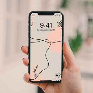 May include: A black smartphone with a white and pink abstract design wallpaper. The time is 9:41 and the date is Tuesday, September 17.
