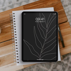 May include: A black tablet with a white leaf design on the screen. The time is 09:41 and the date is Tuesday, September 17. The tablet is sitting on a white notebook with a spiral binding.