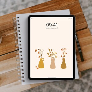 May include: A digital tablet displaying a minimalist phone wallpaper with a white background and three vases with stylized flowers in shades of orange, brown, and yellow. The time is 09:41 and the date is Tuesday, September 17.