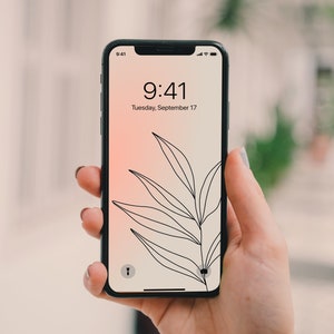 May include: A black smartphone with a white screen displaying the time 9:41 and the date Tuesday, September 17. The background of the screen is a gradient of pink and white with a black line drawing of a leaf.