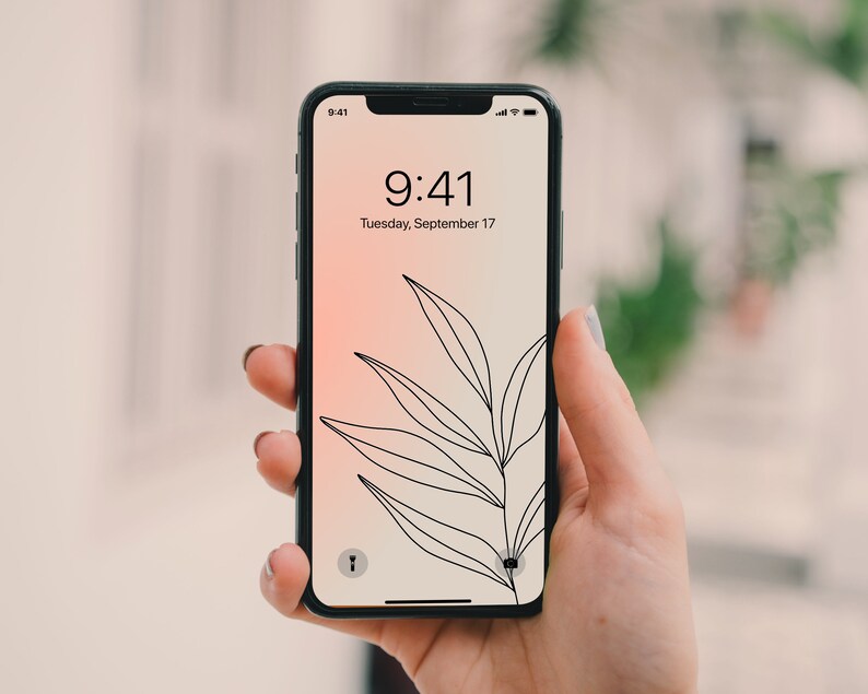 May include: A black smartphone with a white screen displaying the time 9:41 and the date Tuesday, September 17. The background of the screen is a gradient of pink and white with a black line drawing of a leaf.