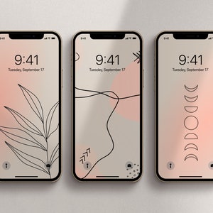 May include: Three iPhone mockups with different minimalist phone wallpapers. The first wallpaper features a black line drawing of a leaf on a gradient background of pink and beige. The second wallpaper features a black line drawing of a curved line and a pink circle on a beige background. The third wallpaper features a black line drawing of a crescent moon in various phases on a gradient background of pink and beige. All three mockups display the time as 9:41 and the date as Tuesday, September 17.