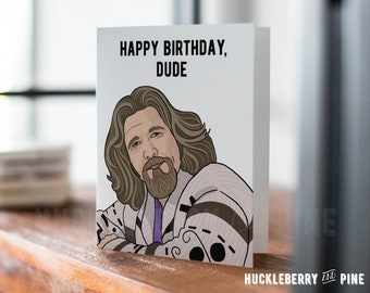May include: Greeting card with the text "HAPPY BIRTHDAY, DUDE" and an illustration of a man with long hair and a beard. The card is white with a cartoon-style image. The HUCKLEBERRY AND PINE logo is at the bottom.