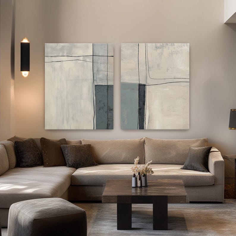Peut inclure: Deux peintures abstraites aux tons neutres et aux d&eacute;tails de lignes noires sont accroch&eacute;es au-dessus d'un canap&eacute; d'angle beige. L'&oelig;uvre pr&eacute;sente des blocs et des lignes gris, blancs et gris fonc&eacute;. Une table basse en bois fonc&eacute; et des coussins d&eacute;coratifs compl&egrave;tent le salon.