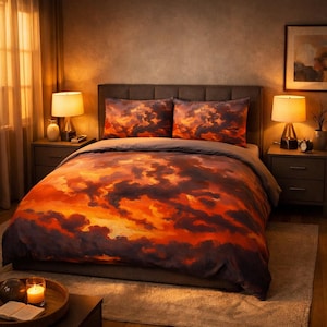 Pode incluir: Um conjunto de roupa de cama com uma estampa de céu ao pôr do sol, apresentando nuvens em tons de laranja profundo, vermelho ardente e roxo escuro. O conjunto inclui uma capa de edredão e duas fronhas a condizer com um padrão dramático.