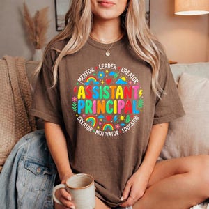 Peut inclure: Une tasse en c&eacute;ramique blanche avec une anse noire et le texte "But First, Coffee" en noir, en gras. La tasse est pos&eacute;e sur une surface blanche. La tasse semble contenir environ 355 ml.