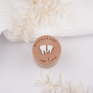 Könnte beinhalten: Eine kleine Holzkiste mit dem Text "MILCHZÄHNE von Lena" auf dem Deckel. Zwei weiße Zahnformen sind auf dem Deckel befestigt.