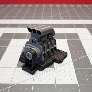 Puede incluir: Un modelo de motor grande de color gris impreso en 3D con cuatro tubos de admisión y una base. El motor está sobre una superficie a cuadros gris y blanca.