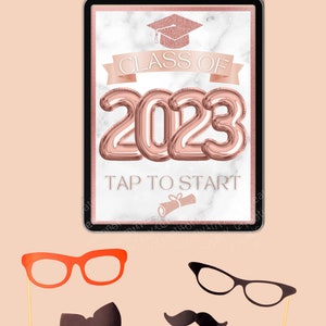 May include: A digital photo booth prop with a rose gold background and the text "Class of 2023" with a graduation cap icon. The text "Tap to Start" is below the year.