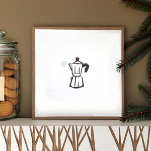 Könnte beinhalten: Ein gerahmter Druck mit einer Schwarz-Weiß-Illustration einer Espressokanne mit Dampf. Das Kunstwerk wird auf weißem Hintergrund in einem Holzrahmen gezeigt. Links ist ein Glas mit Keksen zu sehen, rechts ein Tannenzweig.
