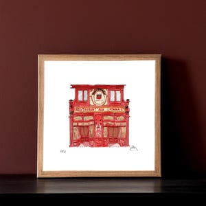 May include: Watercolour painting of a red restaurant facade with the text "Restaurant Aux Lyonnais". The building has multiple windows and a decorative sign above the entrance. The artwork is framed in a wooden frame.