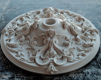 May include: White plaster ceiling medallion with intricate floral and scrollwork designs. The medallion has a circular shape and a raised center with a hole for a light fixture.