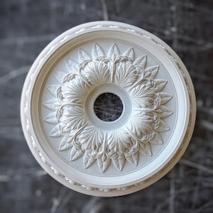 May include: White ceiling medallion with a decorative floral design. The medallion has a circular shape with a central hole for a light fixture.