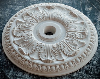May include: White plaster ceiling medallion with a decorative floral design. The medallion has a central hole for a light fixture.