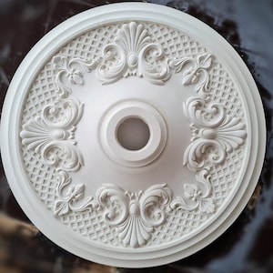 May include: White ceiling medallion with intricate floral and geometric designs. The medallion has a raised center with a circular opening.
