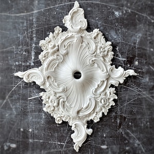 May include: Ornate white ceiling medallion with a central hole, surrounded by detailed floral and scrollwork designs. The decorative plaster element has a symmetrical, circular shape and is set against a dark, textured background.
