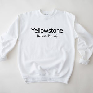 May include: White crewneck sweatshirt with the text "Yellowstone Dutton Ranch" printed in black.