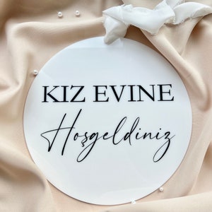 May include: White round sign with black text that reads "KIZ EVINE Hosgeldiniz".